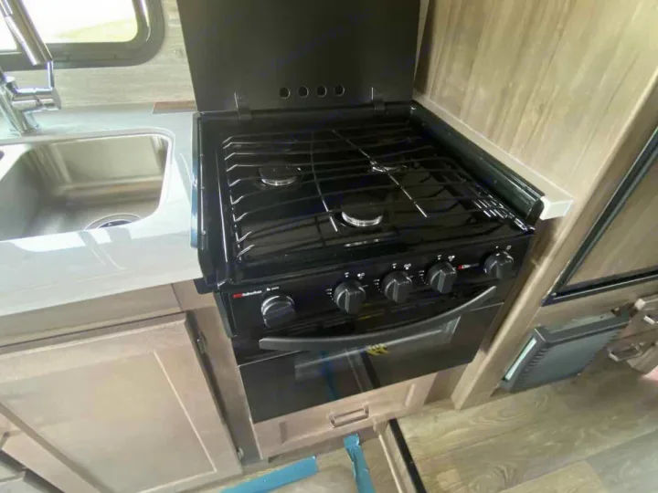 RV rental kitchen features a stainless steel sink, gas stove with oven, and countertop. Compact camper interior.. Winnebago Spirit 22M ( R25085) 2025