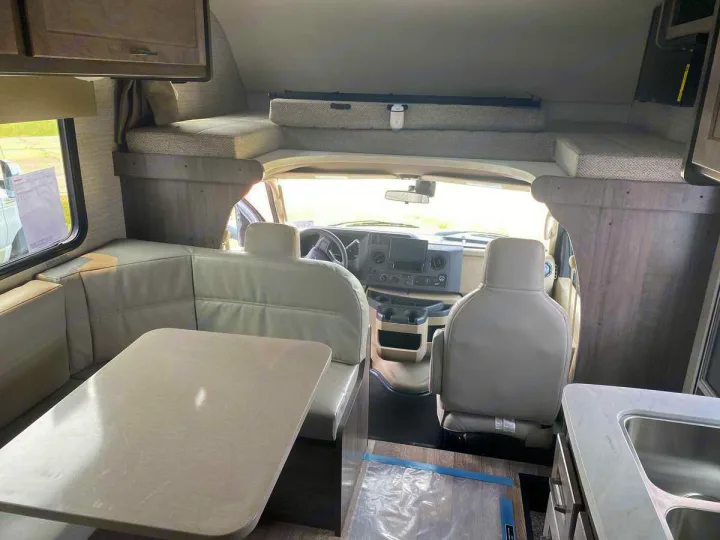 RV rental interior featuring a dinette, cab-over bunk bed, and front cockpit area.. Winnebago Spirit 22M ( R25085) 2025