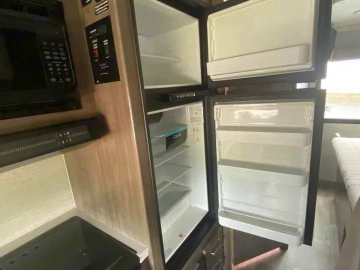 RV rental interior: Open refrigerator, microwave, & control panel in a clean camper kitchen. Ready for your trip!. Winnebago Spirit 22M ( R25085) 2025