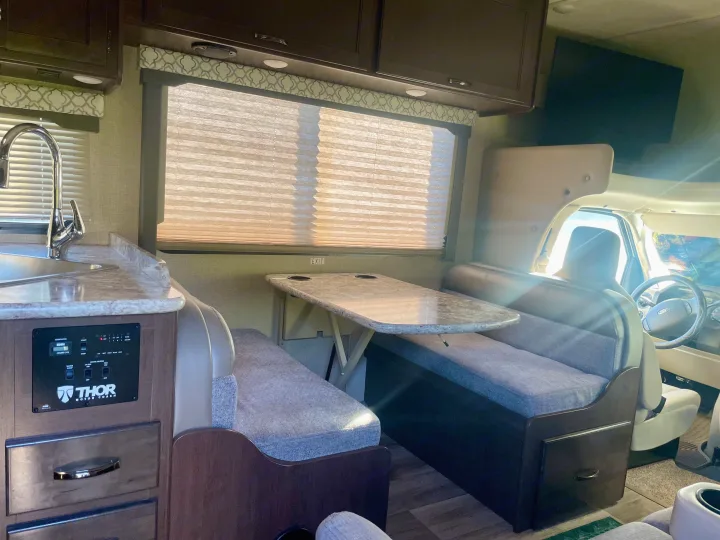 Experience RV rental comfort: full view of a modern motorhome interior, featuring a kitchen, dinette, and cockpit controls.. Thor Freedom Elite 2019