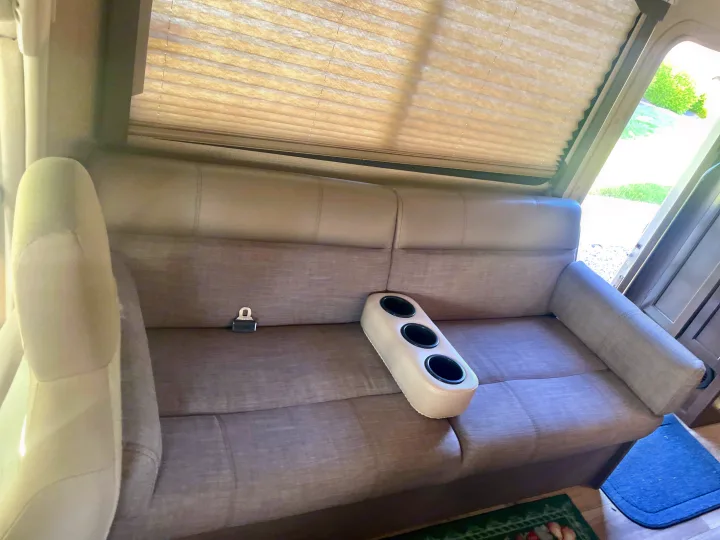This RV rental offers practical sofa seating with a seatbelt and removable cup holder, ideal for travel.. Thor Freedom Elite 2019