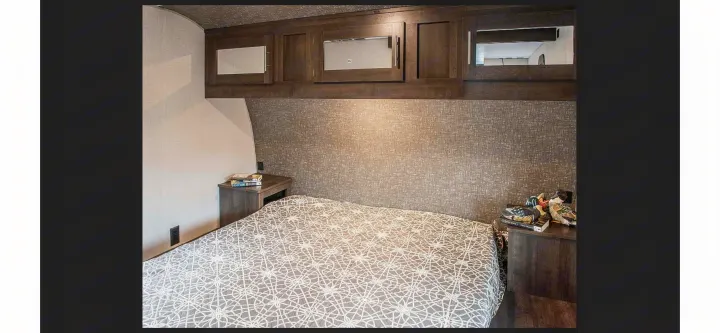 Cozy RV rental bedroom with patterned bedspread, nightstands, and overhead storage. Ideal for comfortable travel.. KZ Sportsmen SE 260BHSE 2020
