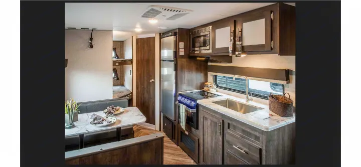 Modern rv rental with compact kitchen, dining booth, and rear bunk beds, ideal for family travel.. KZ Sportsmen SE 260BHSE 2020