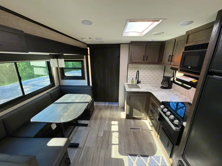 RV rental interior showcasing a modern kitchen, comfortable dinette, and bright skylight.. Jayco Jay Flight 2023