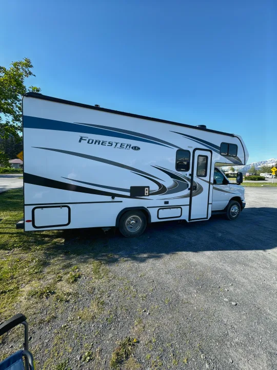 White Forester rv rental parked in a scenic spot, with blue skies & snow-capped mountains visible.. Forester LE 2022