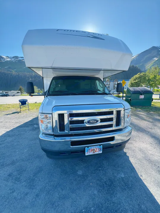 Front view of a white Ford Forester RV rental parked in Alaska, with majestic mountains in the background. Ready for your next adventure.. Forester LE 2022