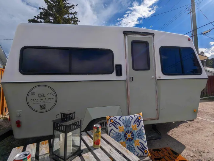 This white & gray "Peas In A Pod" RV rental trailer features an inviting outdoor setup, ready for your next getaway!. Bigfoot DXL 1987