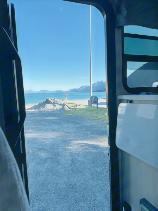 RV rental view of a stunning bay with snow-capped mountains, a person, and a crescent moon in a clear blue sky.. Forester LE 2022