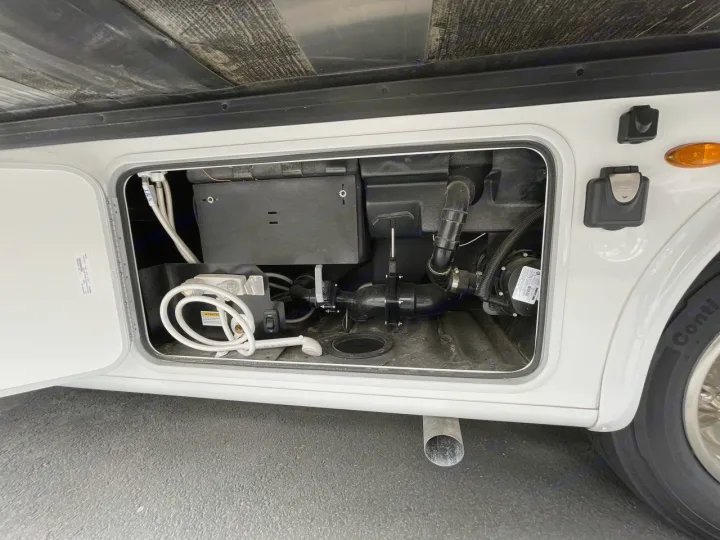 RV rental utility bay open, showing water hookups, hoses, pump, and an outdoor shower. Essential for RV water management.. Thor ACE 2024
