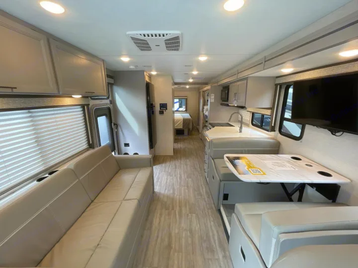 Explore this modern RV rental interior, showcasing a full kitchen, comfy living area, dining space, and rear bedroom.. Thor ACE 2024