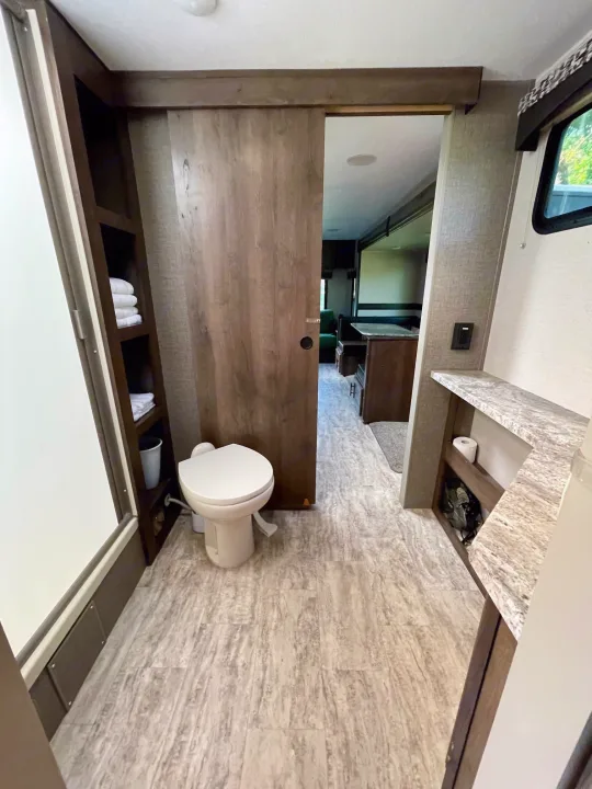 Modern **RV rental** bathroom features toilet, shower, vanity, and storage. Sliding door opens to living area.. Connect 261RL 2018