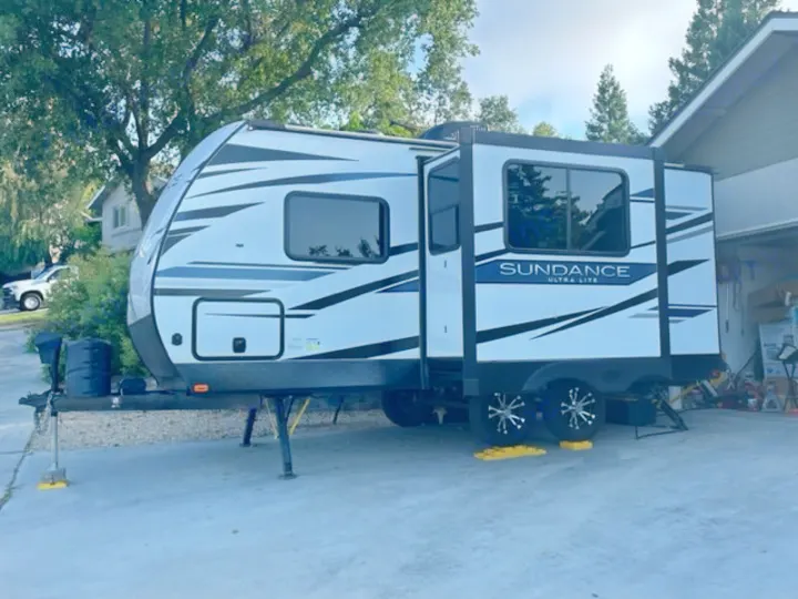 This sleek white Sundance Ultra-Lite travel trailer, with its slide-out extended, is set up for rv rental.. Heartland RVs Other 2022
