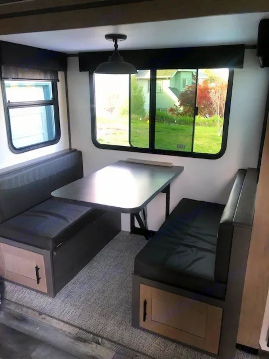 RV rental dinette with cozy booth seating and a table. Windows provide scenic views of the outdoors.. Heartland RVs Other 2022