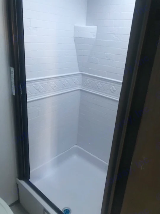 Clean white shower in an RV rental, with brick-look walls, decorative trim, a corner shelf, and shower pan.. Heartland RVs Other 2022