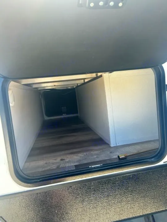 An empty, deep RV rental storage compartment with wood-look flooring and light walls. Perfect for packing gear.. Heartland RVs Other 2022