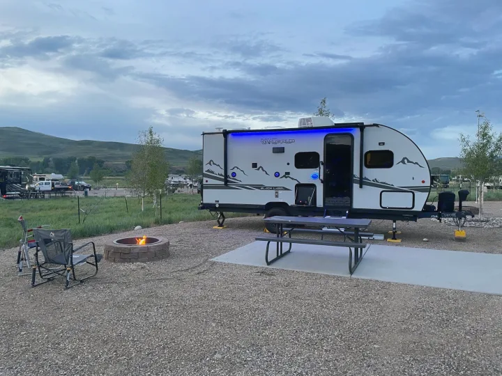 Enjoying a quiet evening at an rv rental campsite, featuring a travel trailer with blue lights, fire pit, and picnic area.. Forest River Cherokee Wolf Pup Black Label 2022