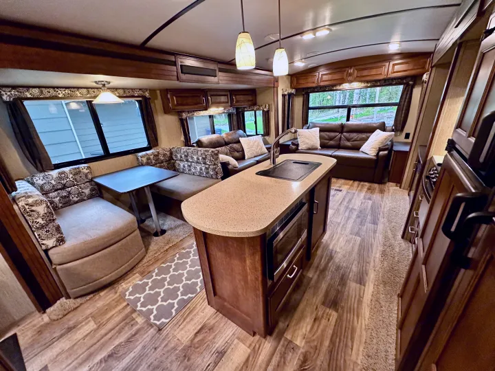 Explore the comfortable interior of this RV rental, featuring a living room, kitchen island, and dinette.. Keystone RV Outback Super-Lite 2018