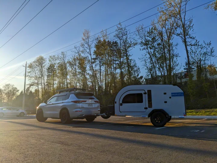 Modern SUV towing a sleek Droplet XL teardrop trailer, a compact rv rental ready for outdoor travel.. DROPLET XL 2024