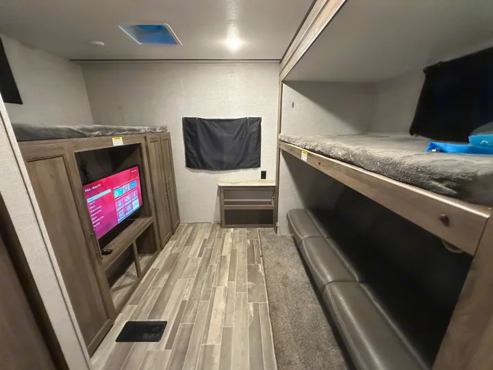 Functional RV rental interior featuring bunk beds, a sofa, and TV for comfortable family living and entertainment.. Crossroads RV Zinger 2021