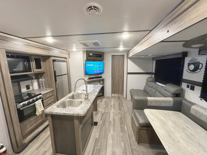 Spacious RV rental interior featuring a modern kitchen island, stove, fridge, and comfortable living area with dinette.. Crossroads RV Zinger 2021
