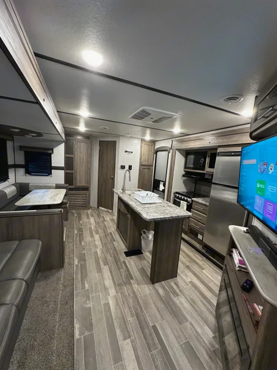 Comfortable rv rental interior showing kitchen island, dinette, and living area with TV.. Crossroads RV Zinger 2021