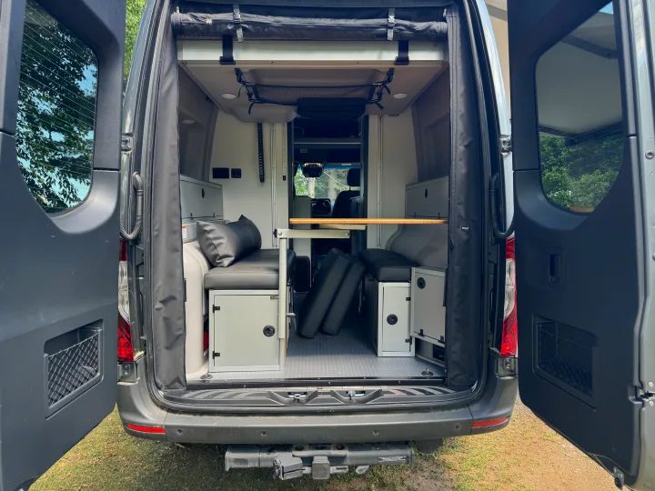 Explore this **RV rental's** versatile **camper van interior** with modular **seating**, **table**, and **storage**, ready for adventure.. Winnebago Revel 2023
