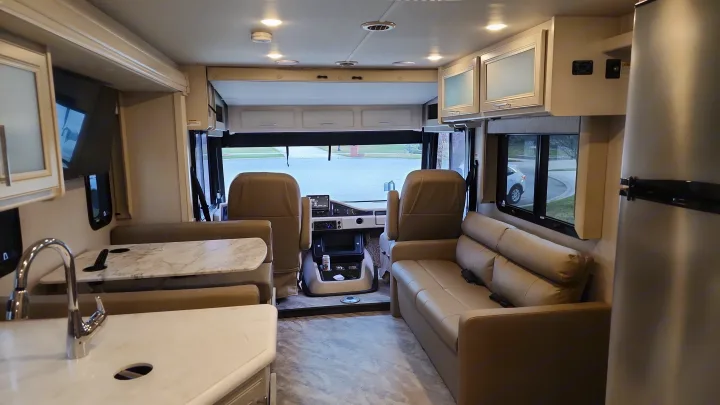 Clean, modern rv rental interior: kitchen, dinette, sofa, and driver's cockpit for spacious travel.. Holiday Rambler Eclipse 2024