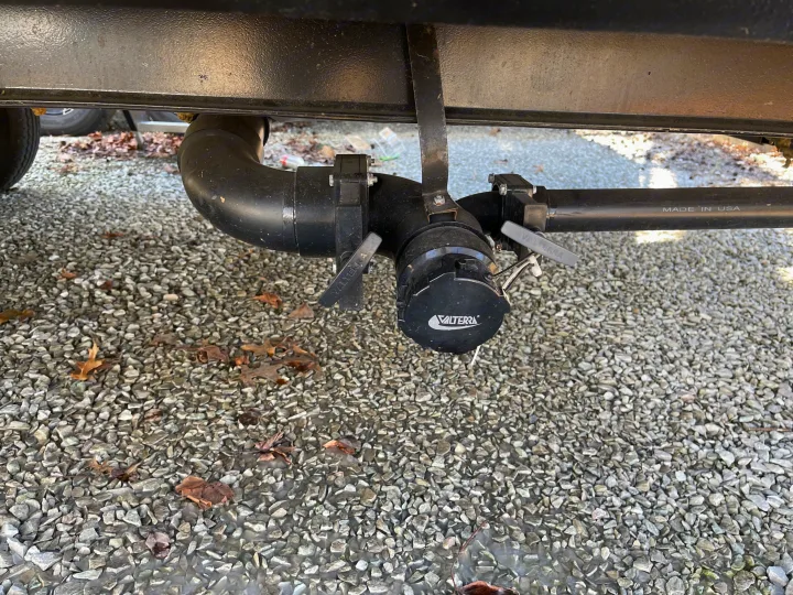 View of an RV rental's Valterra wastewater drainage system, including valves and end cap, on gravel.. Crossroads RV Zinger Lite 2021