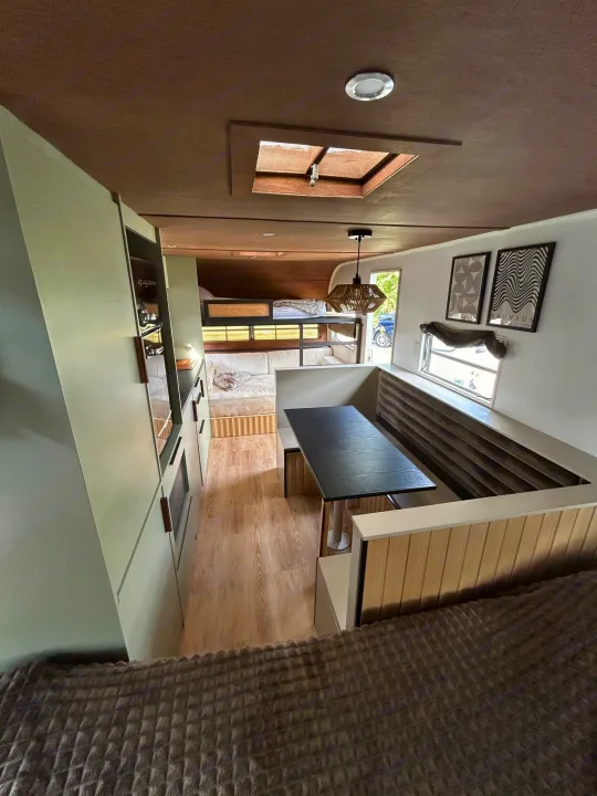 Elevated view of a bright RV rental interior: modern dining nook, sleek sage kitchen, and bunk beds. Perfect for mobile living.. Glendale Golden Falcon 1967