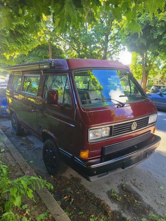 Maroon VW Westfalia camper van, ideal for your next RV rental adventure, parked on E 22nd Ave under sunlit trees.. Volkswagen T3 Mulitvan 1991