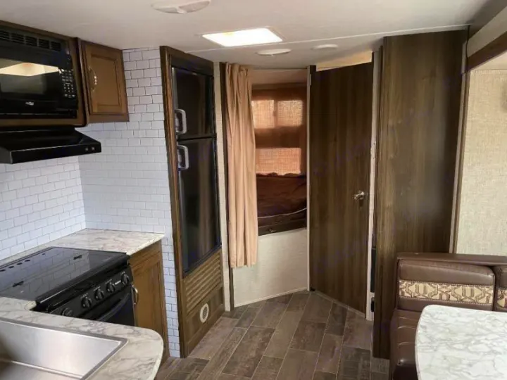 RV rental interior showcasing a well-equipped kitchen, comfortable dinette, and private bedroom.. Keystone RV Bullet Ultra Lite 2018