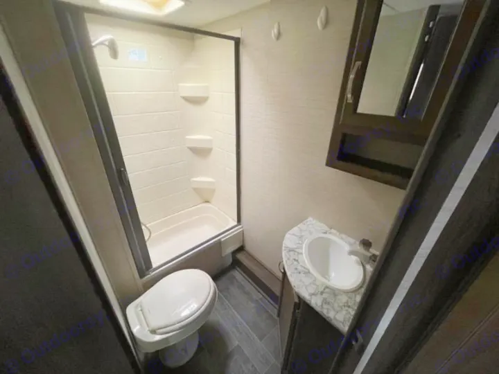 This compact RV rental bathroom features a shower, toilet, sink vanity, and mirrored cabinet, optimized for travel.. Keystone RV Bullet Ultra Lite 2018