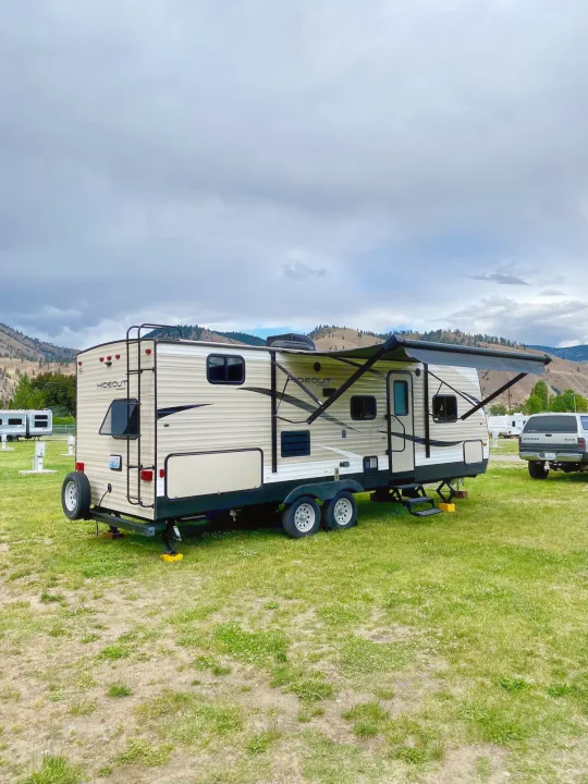Spacious Hideout RV rental parked at a scenic campground with mountains under a cloudy sky. Perfect for outdoor adventures.. Keystone RV Hideout 2018