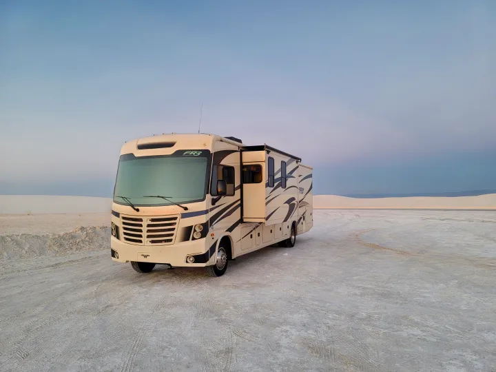 A white RV rental motorhome with extended slide-out, parked on the gypsum dunes of White Sands National Park.. Forest River FR3 2020