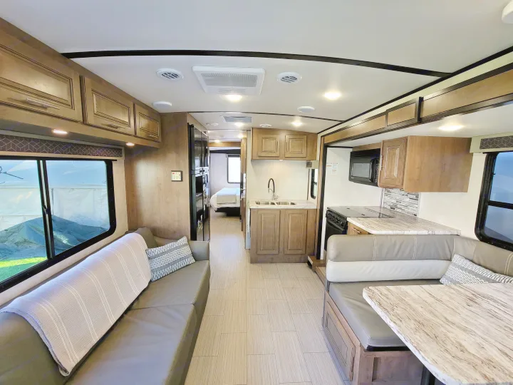 Spacious RV rental interior featuring a modern living area, full kitchen, dining booth, and visible bedroom.. Forest River FR3 2020