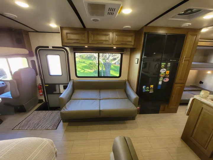 Comfortable RV rental interior with a flat sofa-bed, kitchen, bunk beds, and scenic views, perfect for trips.. Forest River FR3 2020