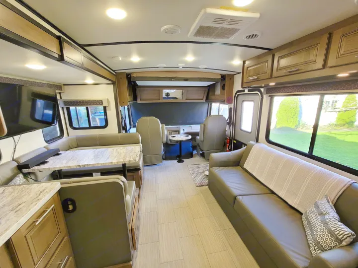 Spacious RV rental interior: a modern living space featuring a dinette, comfortable sofa, and compact kitchen area. Ideal for travel.. Forest River FR3 2020