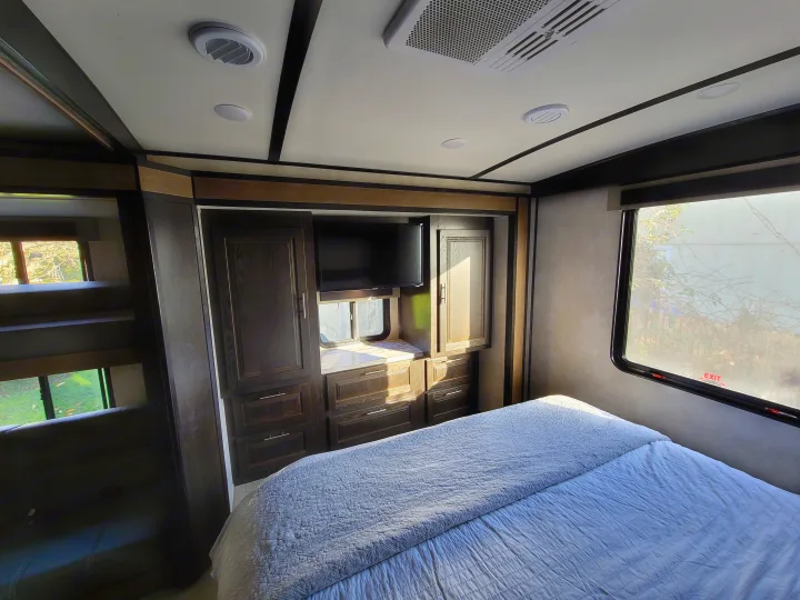 Spacious RV rental interior showcasing a cozy bedroom with bed, TV, built-in storage, and adjacent bunk beds.. Forest River FR3 2020