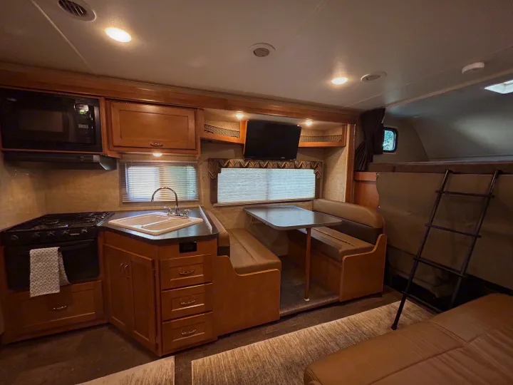 Well-equipped RV rental interior with a kitchen, dinette, and bunk beds, perfect for your next camper adventure.. Winnebago Minnie Winnie 2017