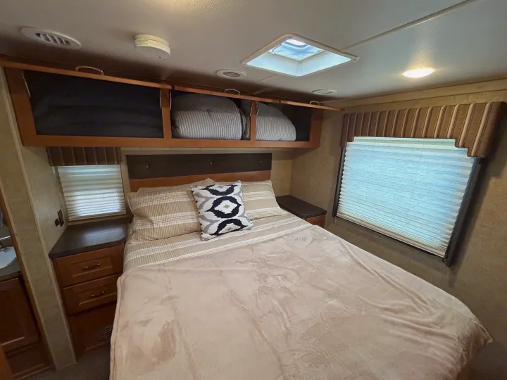 Enjoy this RV rental's cozy bedroom with a comfortable bed, convenient overhead storage, and natural light from the window.. Winnebago Minnie Winnie 2017