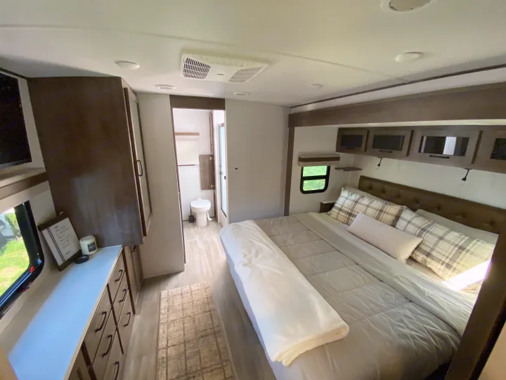 Cozy, modern RV rental bedroom with a comfortable bed, ample storage, and private bathroom. Ready for adventure!. Forest River Rockwood Signature 2024