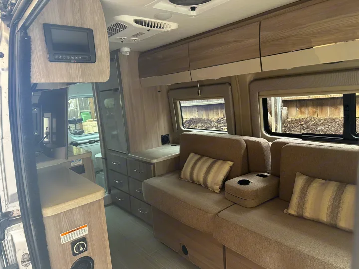 Modern RV rental interior with comfy seating, woodgrain cabinets, and BMPRO controls. Enjoy mobile living convenience!. Thor Sequnce 2023
