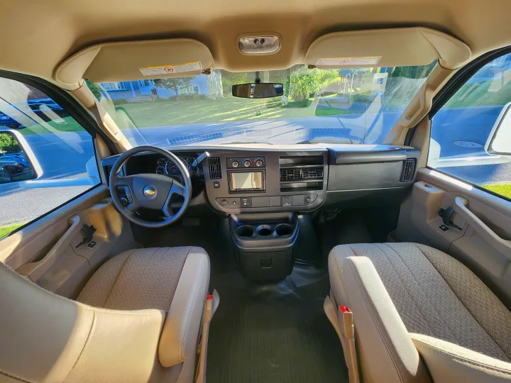 Bright and spacious front cabin of an RV rental, featuring driver's cockpit, passenger seat, and clear road ahead.. Thor Four Winds 2024