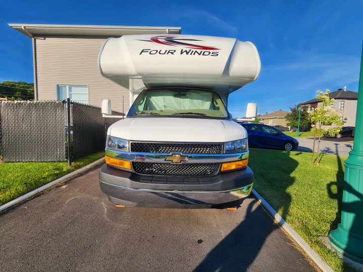 White Four Winds Chevrolet RV, head-on view, parked on a driveway. Perfect for an rv rental adventure.. Thor Four Winds 2024