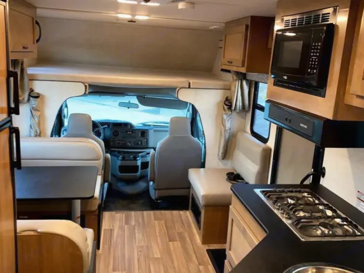 Spacious RV rental interior, featuring a full kitchen, dinette, cockpit, and overhead bunk. Ideal for road trips.. Tiffin Motorhomes Wayfarer 2021
