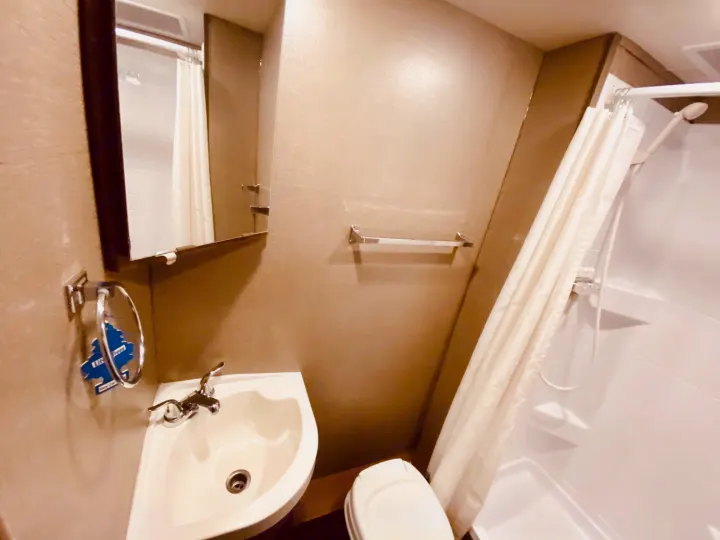 This rv rental bathroom features a compact sink, mirror, toilet, and shower, optimizing space for your journey.. Winnebago 25J 2019
