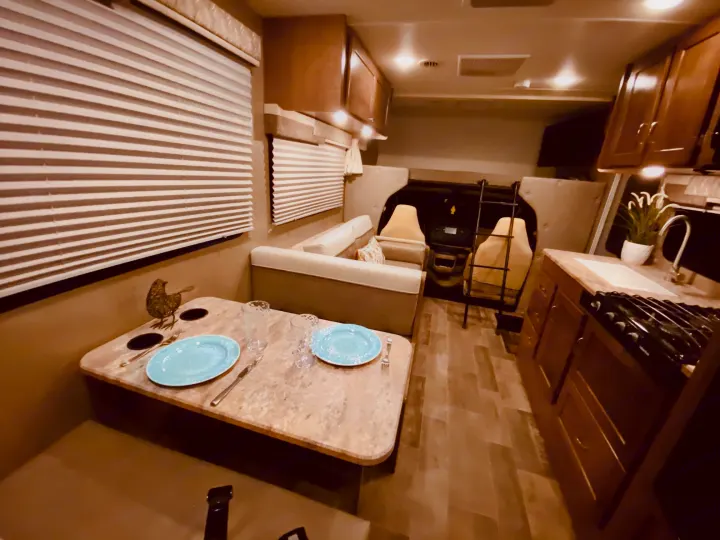 Cozy RV rental interior: a dinette with place settings, full kitchen, and front bunk area create a comfortable travel space.. Winnebago 25J 2019