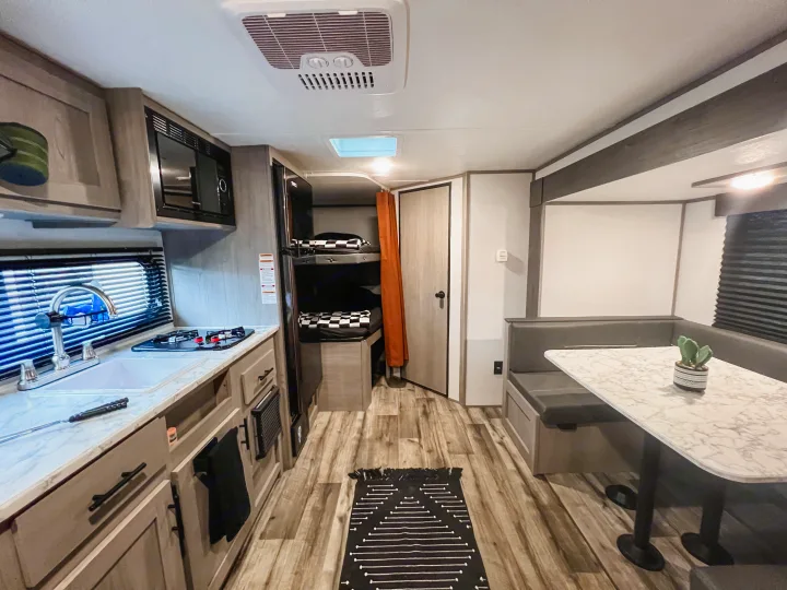 Cozy RV rental interior showcasing a compact kitchen, U-shaped dinette, and bunk beds for family comfort.. Dutchmen Lantern LT BB19 2024