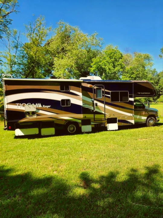 Experience freedom with this Tioga Ranger Fleetwood RV rental. Parked on lush grass under a blue sky, ready for your next journey.. Tioga Ranger 2013