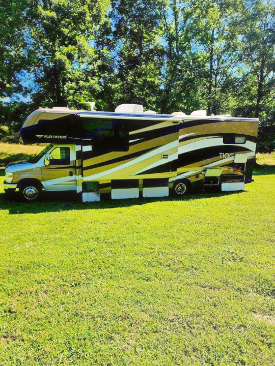 Beautiful Fleetwood Tioga Class C rv rental with gold and black design, parked on a sunny green lawn, ready for adventure.. Tioga Ranger 2013